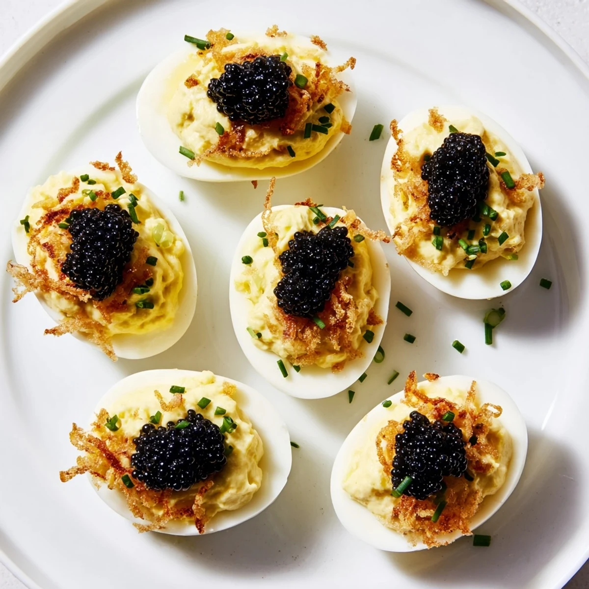 Creamy deviled eggs, adorned with luxurious caviar and crispy shallots; a delightful party dish.