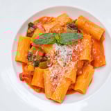 A creamy pot of Hidden Veggie Tomato Pasta Sauce ready to coat steaming spaghetti, featuring a vibrant orange-red hue and a wooden spoon.