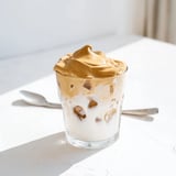 Rich, creamy whipped Dalgona coffee floats over cold milk in a clear glass, inviting a refreshing sip.