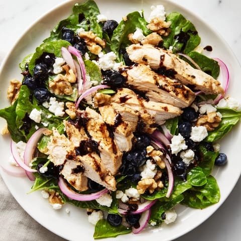 A beautiful bowl of Blueberry Goat Cheese Chicken Salad with vibrant mixed greens and crunchy walnuts for a light lunch.