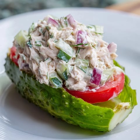 Juicy chicken salad spilling from hollowed pickles, a creative take on the pickle sandwich.
