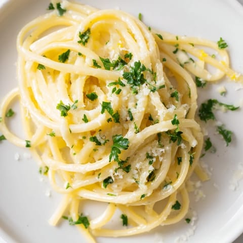 This vibrant plate of Lemon-Garlic Greek Yogurt Pasta features a creamy sauce and Parmesan cheese.