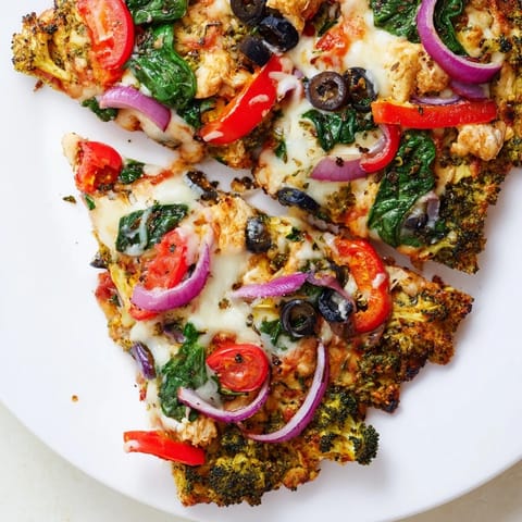 A close-up of Broccoli Chicken Crust Pizza slices on a wooden board, revealing melted mozzarella and vibrant vegetable toppings.
