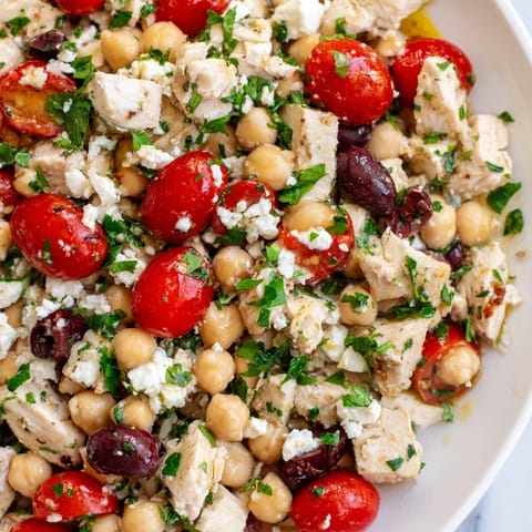 A colorful bowl of Mediterranean Chickpea Chicken Salad features creamy feta, cherry tomatoes, and chickpeas tossed in a zesty lemon-oregano dressing.  