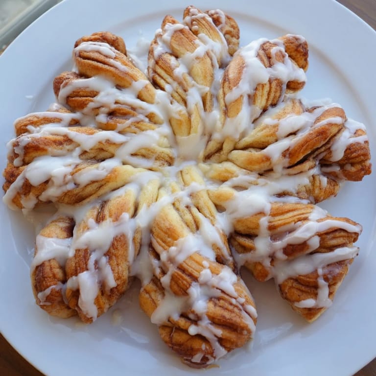 Drizzled icing over a perfectly shaped Cinnamon Roll Pull-Apart Snowflake, smelling of sweet cinnamon and vanilla.