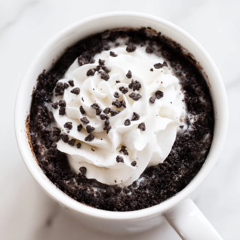 A rich, fluffy Oreo mug cake, freshly made and ready to enjoy straight from the mug.