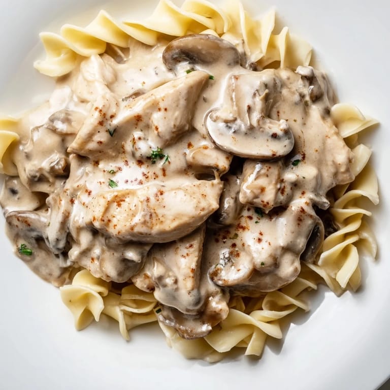 For a comforting dinner, enjoy this Russian-inspired Chicken and Mushroom Stroganoff served steaming hot, garnished with fresh parsley.